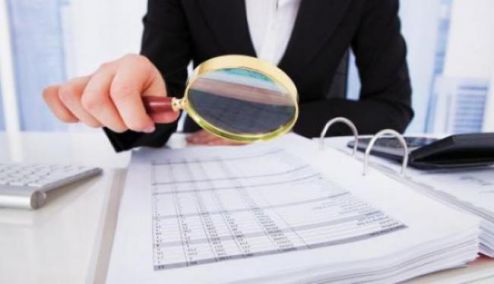 man looking at numbers with magnifying glass